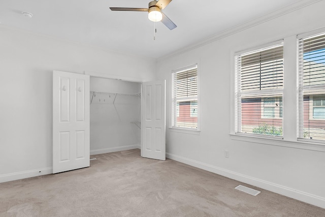 unfurnished bedroom featuring multiple windows, light carpet, and ceiling fan