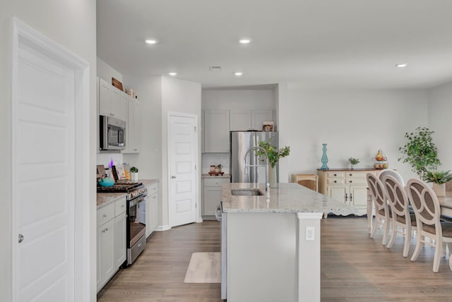 kitchen featuring a center island with sink, sink, appliances with stainless steel finishes, and hardwood / wood-style flooring