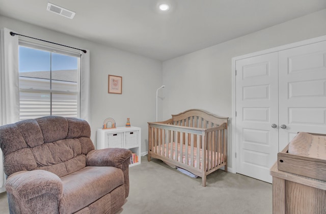 bedroom with light carpet, a closet, and a nursery area