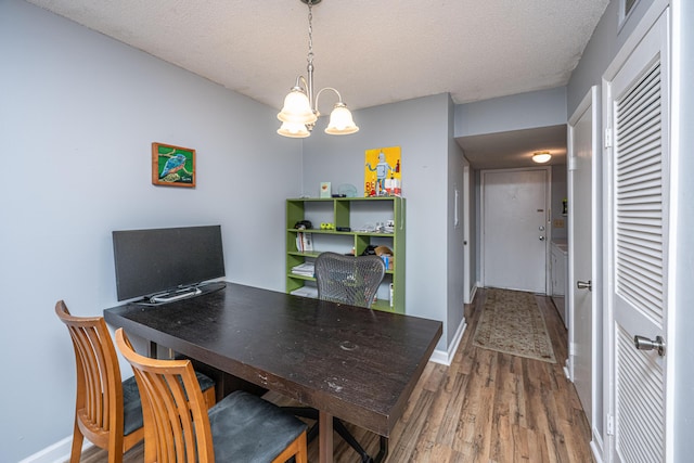 dining area featuring an inviting chandelier, wood finished floors, baseboards, and a textured ceiling