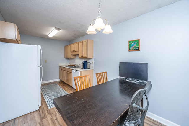 kitchen featuring a sink, white appliances, light brown cabinets, and light wood finished floors