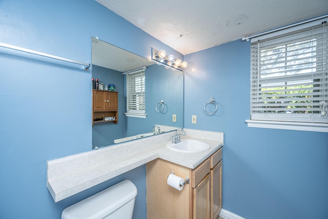 bathroom with baseboards, toilet, vanity, and a textured ceiling