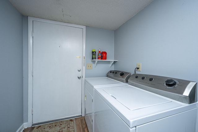 laundry area with a textured ceiling, wood finished floors, laundry area, and washing machine and clothes dryer