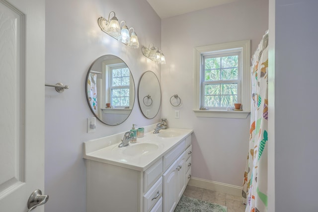 bathroom featuring tile patterned flooring, double vanity, baseboards, and a sink