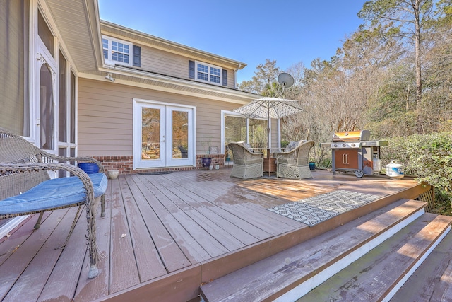 wooden deck with french doors, a grill, and outdoor dining space