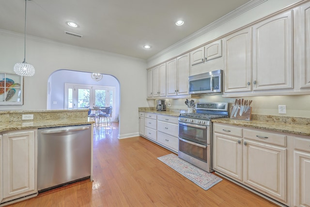 kitchen with decorative light fixtures, arched walkways, appliances with stainless steel finishes, crown molding, and light wood finished floors