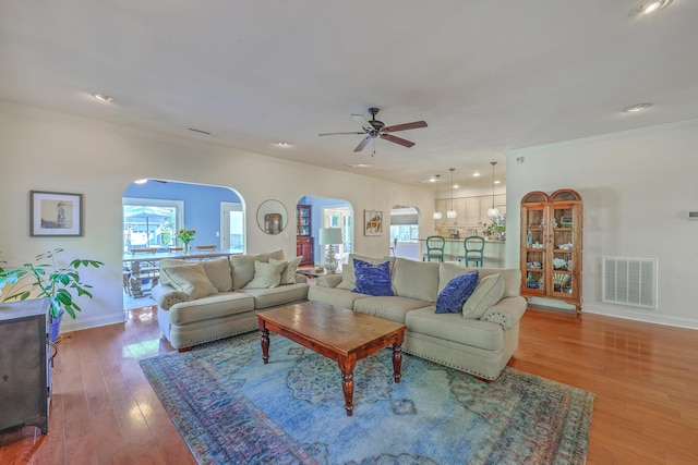 living room featuring visible vents, arched walkways, a healthy amount of sunlight, and a ceiling fan