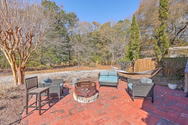 view of patio with an outdoor living space with a fire pit and fence