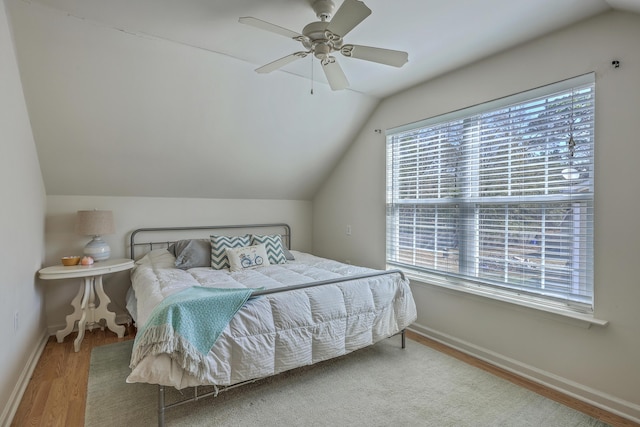 bedroom with vaulted ceiling, wood finished floors, baseboards, and ceiling fan