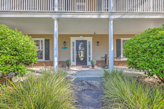 doorway to property with brick siding and a porch