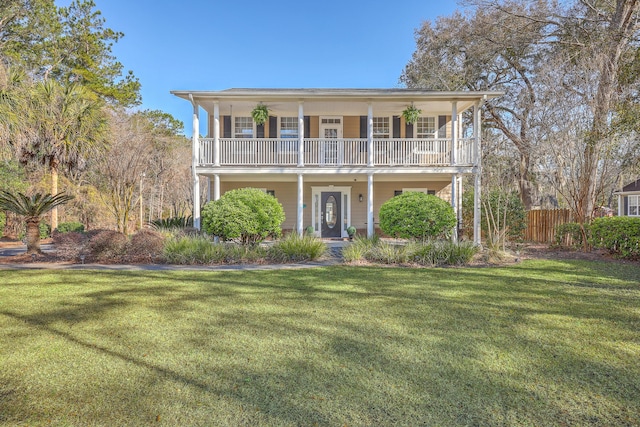 view of front of property featuring a balcony, a front lawn, and fence