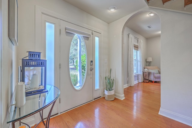 entrance foyer with visible vents, wood finished floors, arched walkways, and baseboards