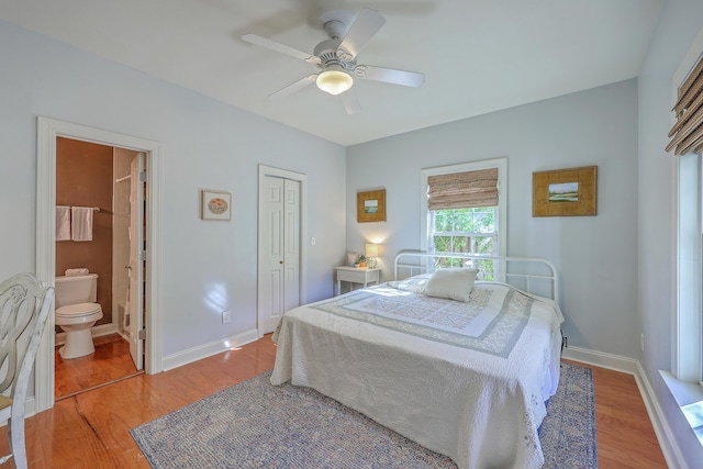 bedroom featuring ensuite bath, a closet, light wood finished floors, baseboards, and ceiling fan