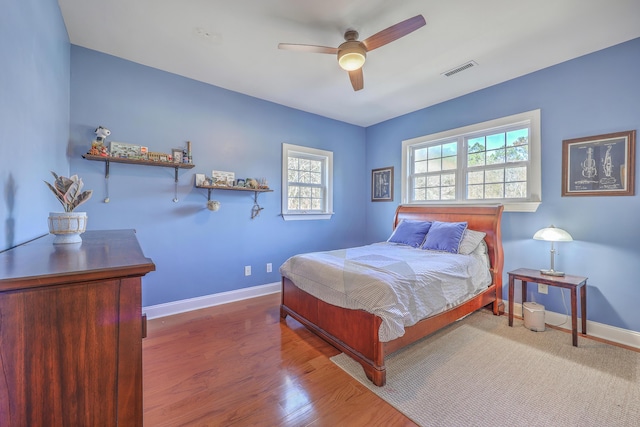 bedroom with visible vents, a ceiling fan, baseboards, and wood finished floors