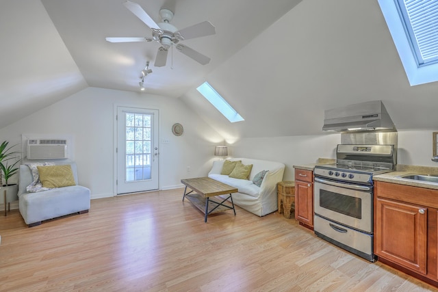 kitchen with ventilation hood, vaulted ceiling with skylight, light wood-style flooring, stainless steel gas stove, and open floor plan