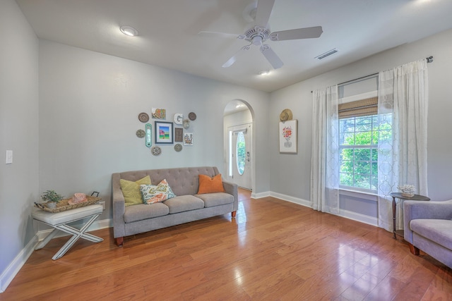 living area with visible vents, wood finished floors, arched walkways, baseboards, and ceiling fan