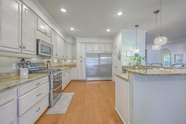 kitchen with light stone countertops, light wood-style flooring, recessed lighting, appliances with stainless steel finishes, and decorative light fixtures