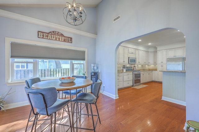 dining space with wood finished floors, visible vents, arched walkways, and baseboards