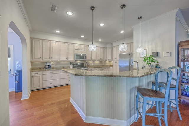 kitchen with visible vents, a peninsula, light wood-style flooring, arched walkways, and stainless steel appliances