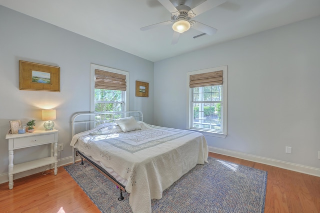 bedroom with a ceiling fan, light wood-style flooring, baseboards, and visible vents