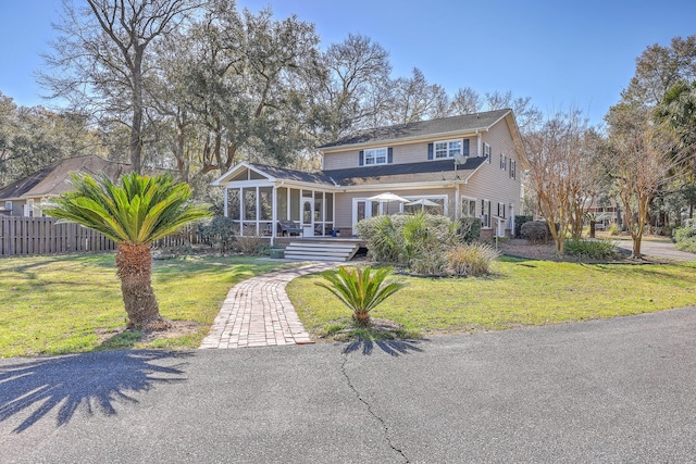 view of front of home with a front lawn, fence, and a sunroom