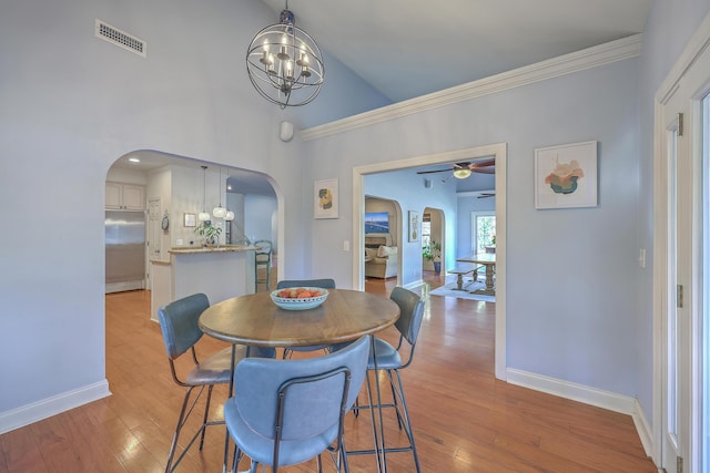 dining room with ceiling fan with notable chandelier, visible vents, arched walkways, and light wood-type flooring