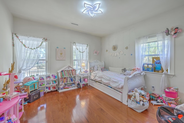 bedroom featuring multiple windows, wood finished floors, and visible vents