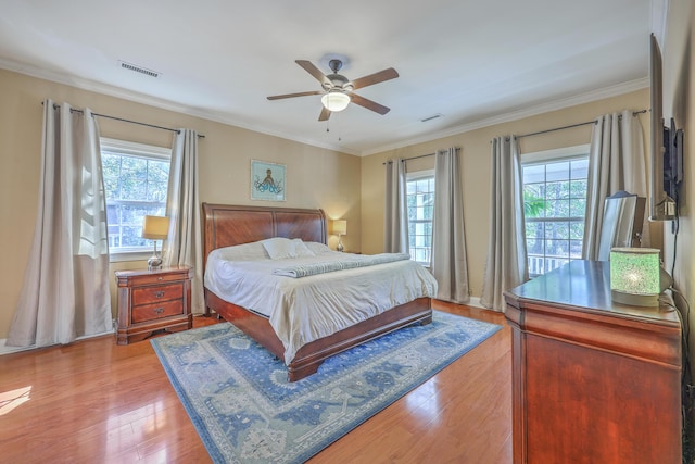 bedroom featuring multiple windows, light wood-style floors, visible vents, and ornamental molding