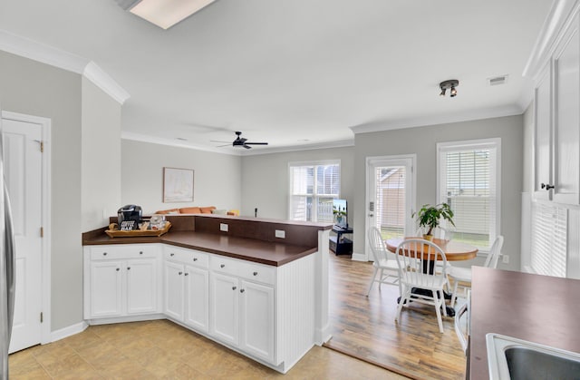 kitchen with ceiling fan, light hardwood / wood-style floors, ornamental molding, and white cabinetry