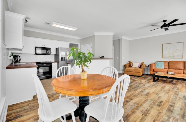 dining area with crown molding, sink, ceiling fan, and light hardwood / wood-style flooring