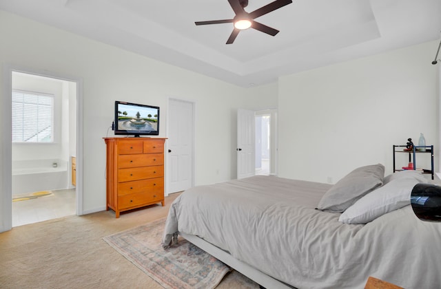 carpeted bedroom with connected bathroom, ceiling fan, and a raised ceiling