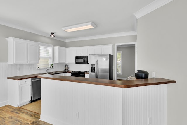 kitchen with black appliances, kitchen peninsula, plenty of natural light, and white cabinets