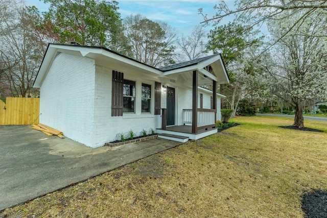 view of front facade with brick siding, fence, and a front lawn