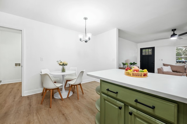 kitchen featuring baseboards, open floor plan, light countertops, light wood-type flooring, and green cabinets