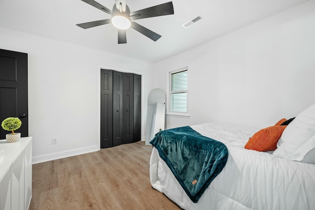 bedroom featuring light wood finished floors, a closet, visible vents, a ceiling fan, and baseboards