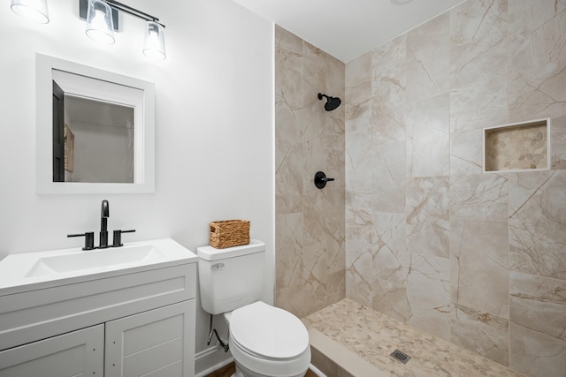 full bathroom with tiled shower, vanity, and toilet