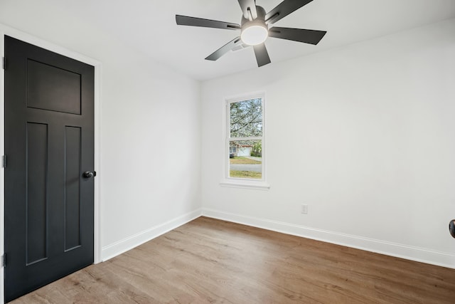 empty room with ceiling fan, light wood-type flooring, and baseboards