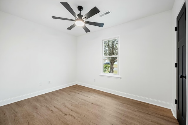 unfurnished room with baseboards, visible vents, ceiling fan, and wood finished floors