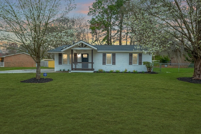 single story home featuring brick siding, a lawn, and fence