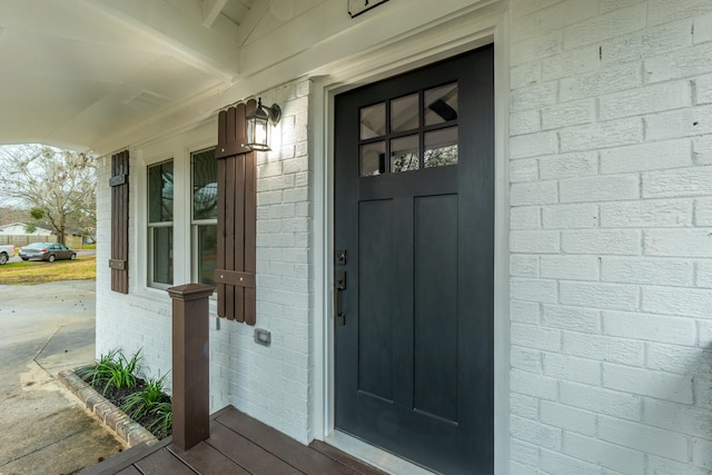 entrance to property with covered porch and brick siding