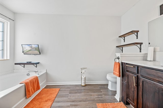 bathroom with toilet, baseboards, a bath, and wood finished floors