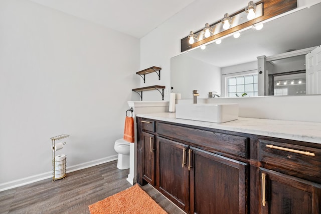 bathroom with baseboards, vanity, toilet, and wood finished floors