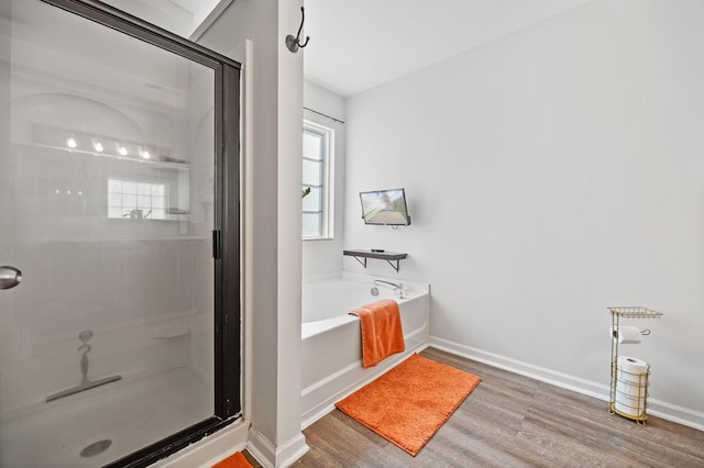 full bath featuring baseboards, a shower stall, a bath, and wood finished floors