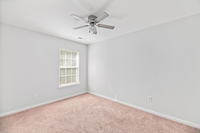 spare room with light carpet, ceiling fan, visible vents, and baseboards