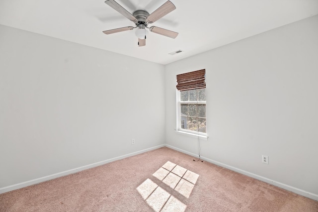 spare room featuring light colored carpet, ceiling fan, visible vents, and baseboards