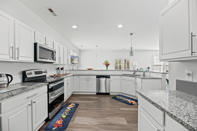 kitchen with a peninsula, a sink, visible vents, white cabinets, and appliances with stainless steel finishes