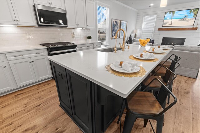 403 Cool Bend Ln, Summerville, SC 29486 - kitchen with stainless steel microwave, a sink, crown molding, light wood-type flooring, and a kitchen breakfast bar