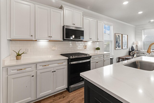 403 Cool Bend Ln, Summerville, SC 29486 - kitchen with range with gas stovetop, stainless steel microwave, wood finished floors, crown molding, and white cabinetry