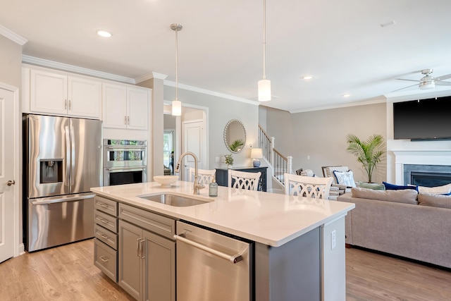 3173 Hugh Bennett Dr, Johns Island, SC 29455 - kitchen with stainless steel appliances, a sink, open floor plan, light wood-style floors, and ornamental molding