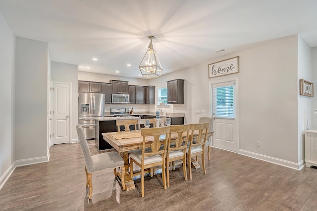dining room with baseboards, visible vents, wood finished floors, and a notable chandelier